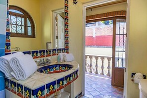 A bathroom with a tiled sink, a mirror, and a towel rack. - Maito Suite - Romantic Zone (Puerto Vallarta)