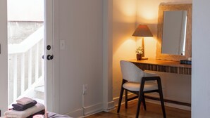 Un dormitorio con cama, un escritorio con lámpara, una silla y un ventilador de techo.