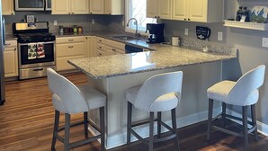 A kitchen with a central island, bar stools, a microwave, oven, and a 'HAPPY HOLIDAYS' sign. - Epic Mountain Views! Cool Weekend Retreat • Pet Friendly Near Charlette (Morganton)