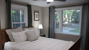 A bedroom with a bed, a nightstand, a lamp, a ceiling fan, and a window with curtains. - The Foxboro Game Day House — 7 Min to Gillette (Foxborough)
