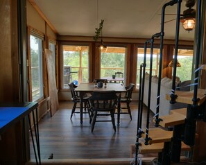 A wooden interior with a dining table, chairs, and a sofa.