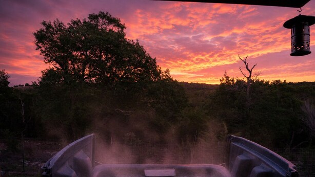 Ein Whirlpool mit Blick auf einen Sonnenuntergang und Bäume.