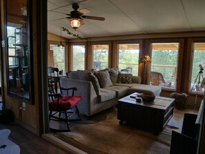A cozy living room with a sectional sofa, a rocking chair, a coffee table, and a ceiling fan.