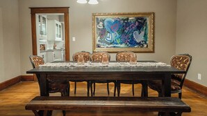 Comedor con una mesa de madera oscura, seis sillas y un cuadro abstracto grande en la pared.
