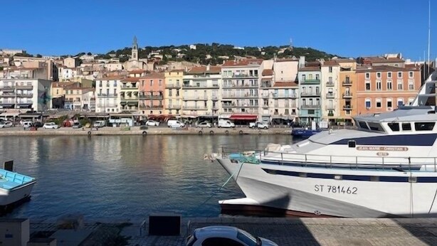 A marina with a white yacht named ST 781462 docked, a row of colorful buildings in the background, and a clear blue sky. - L'Atelier des Merveilles - Sur le port de Sète (Sète)