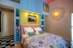 Ein Schlafzimmer mit einem Bett, einem Gemälde, Regalen mit Büchern und einem karierten Boden.