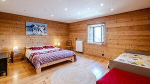 Ein Zimmer mit Holzwänden, zwei Betten, einem großen Gemälde und einem Fenster.