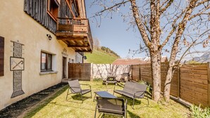 Ein Gebäude mit einem Balkon, einer Terrasse mit Stühlen und einem Holzzaun.