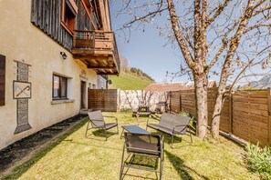 A building with a balcony, a patio with chairs, and a wooden fence. - Le Col de Feu - Joli duplex pour 8 avec jardin (Lullin)