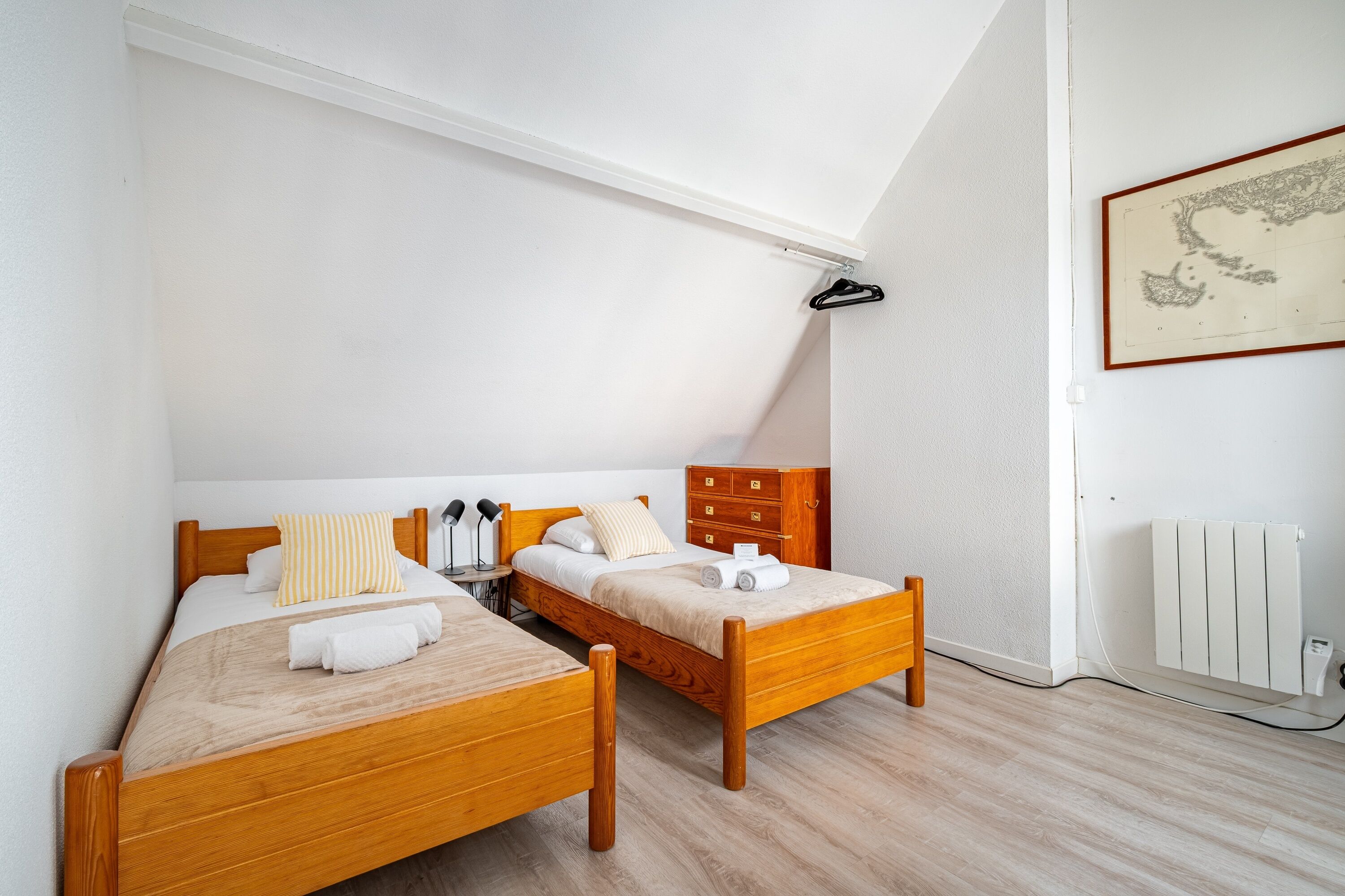 A room with two wooden beds, a white radiator, and a map on the wall.