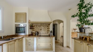Een keuken met een ingebouwde oven, een spoelbak en een groot eiland met lades.