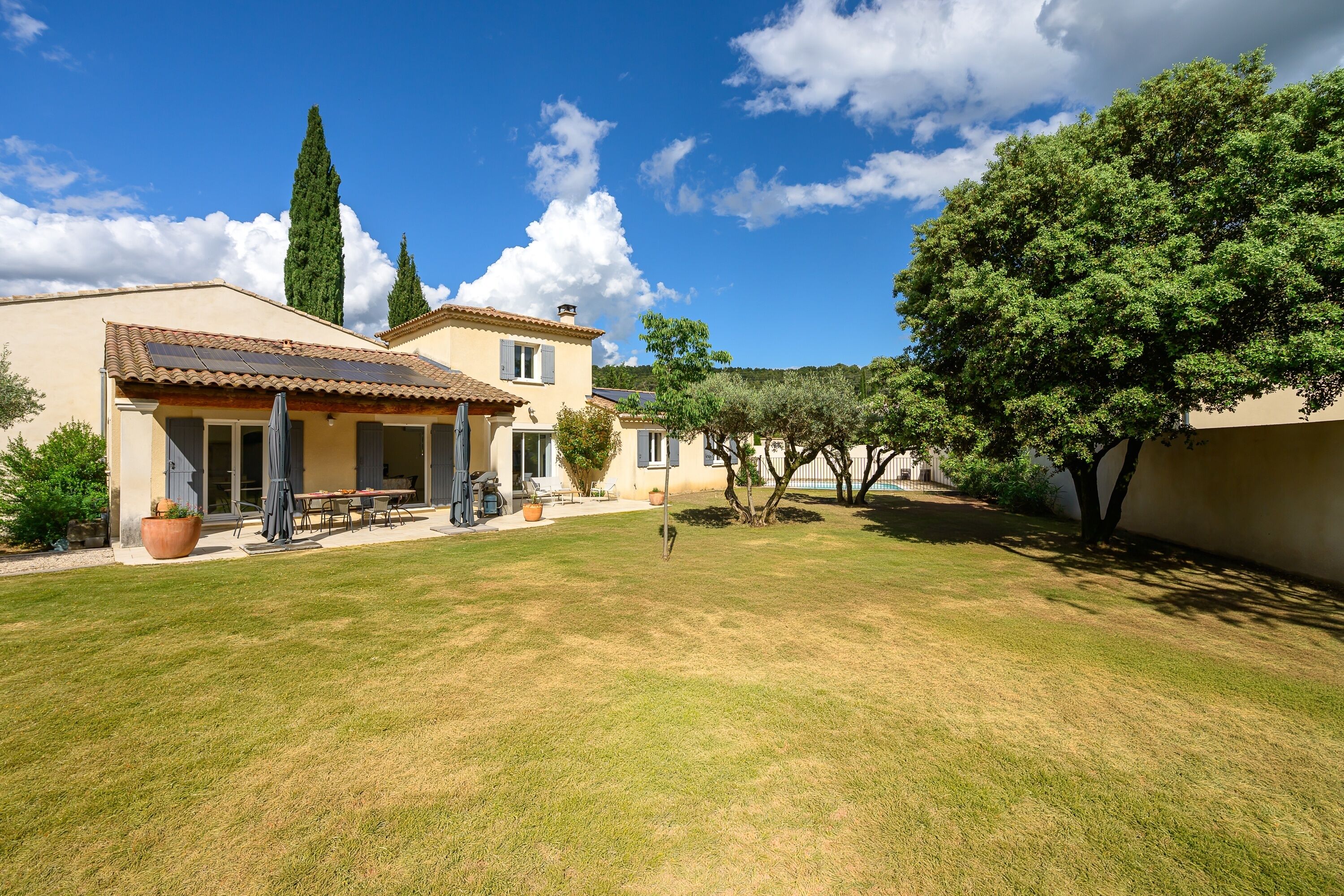 Une maison avec un patio, une pelouse et un arbre.