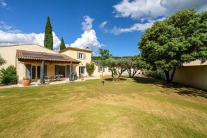 Ein Haus mit Terrasse, Rasen und Baum.