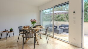 A modern dining area with a round table, chairs, and a potted plant. - Les Oliviers du Papet - Le Nid (Châteaurenard)