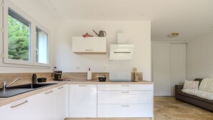 Een moderne keuken met witte kasten, een inbouwoven en een raam.