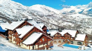 A mountain lodge with multiple wooden buildings, a swimming pool, and snow-covered mountains in the background. - Les Alpages du Corbier B108 - Télésièges à 250 m (Villarembert)