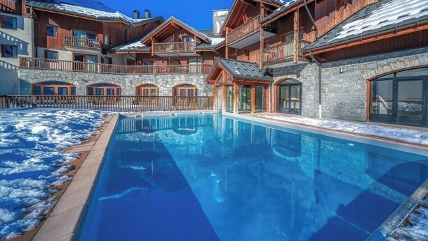 A hotel with a pool, stone walls, wooden balconies, and a clear blue sky. - Les Alpages du Corbier B108 - Télésièges à 250 m (Villarembert)