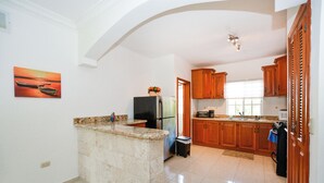 Una cucina con mobili in legno, un piano di lavoro in granito, un frigorifero e un quadro appeso al muro.