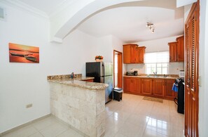 Eine Küche mit Holzschränken, einer Granitarbeitsplatte, einem Kühlschrank und einem Bild an der Wand.