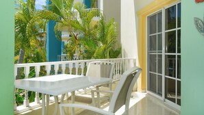Un balcone con tavolo e sedie bianche, immerso nel verde tropicale.