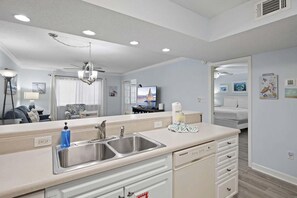 A modern kitchen with a central island, a built-in dishwasher, and a ceiling fan. - Chateau La Mer #13a (Destin)