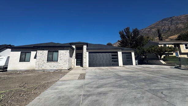 Une maison d’habitation avec une façade en pierre, un garage et une allée.
