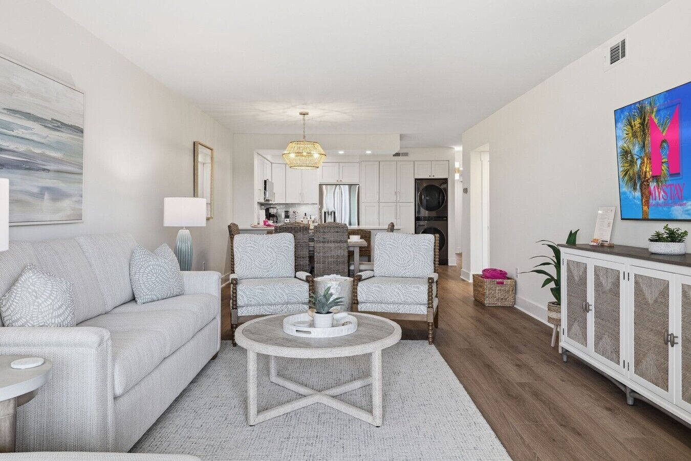 Ein modernes Wohnzimmer mit einer Couch, Sesseln, einem Couchtisch und einer Küche im Hintergrund.