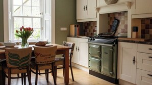 A kitchen with white cabinets, a stove, and a dining area with chairs and a table.