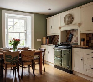 A kitchen with white cabinets, a stove, and a dining area with chairs and a table.