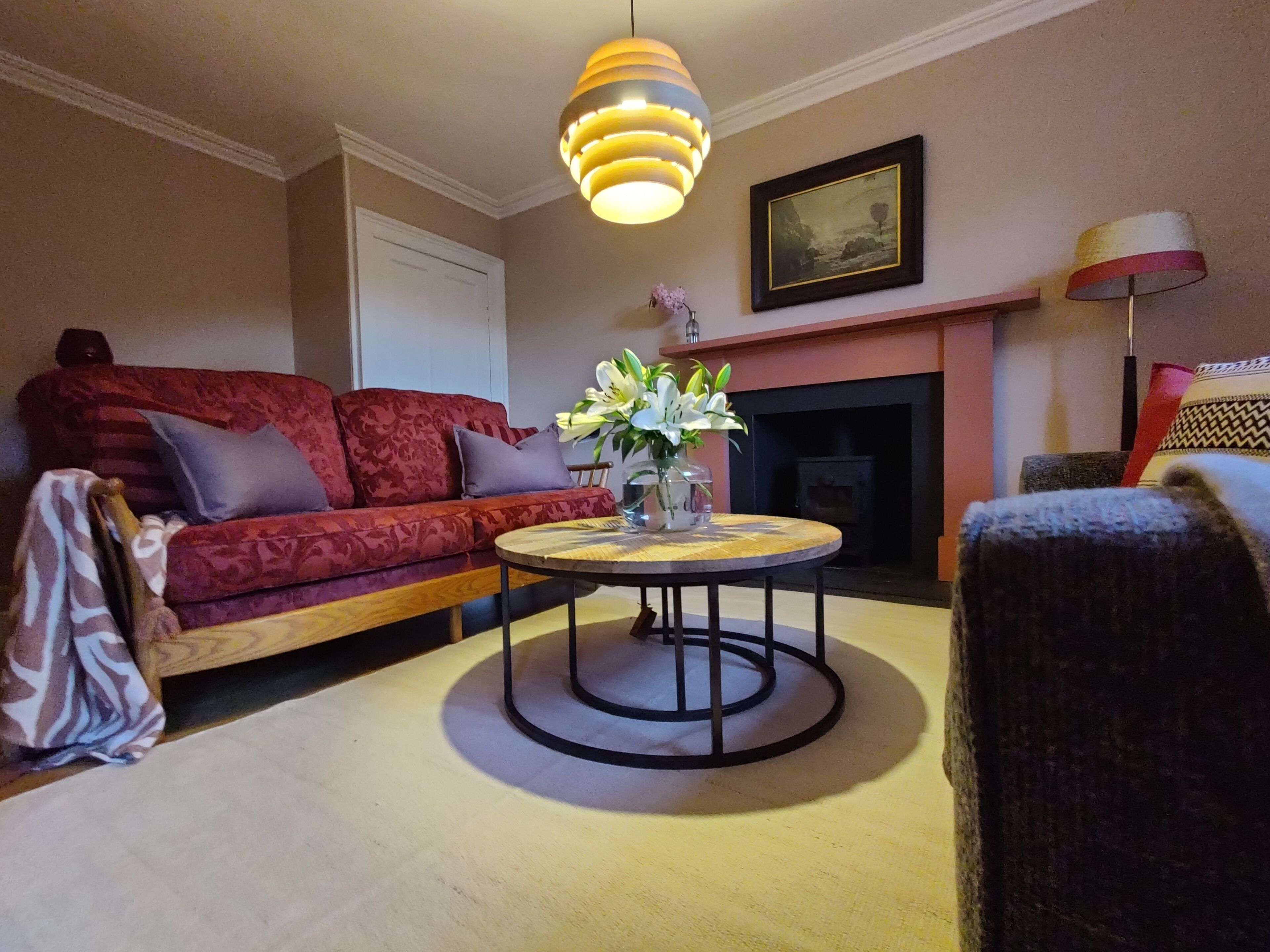A living room with a sofa, a round coffee table, a fireplace, and a hanging light fixture.