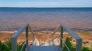 Eine Treppe führt zu einem Strand mit Blick auf das Meer.