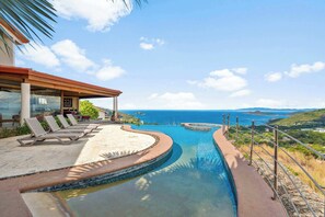 Ein Pool mit Meerblick, Liegestühle und ein überdachter Bereich mit einer Pergola.