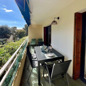 Ein Balkon mit Tisch für zwei Personen, Stühlen, einer Flasche und einem Glas.