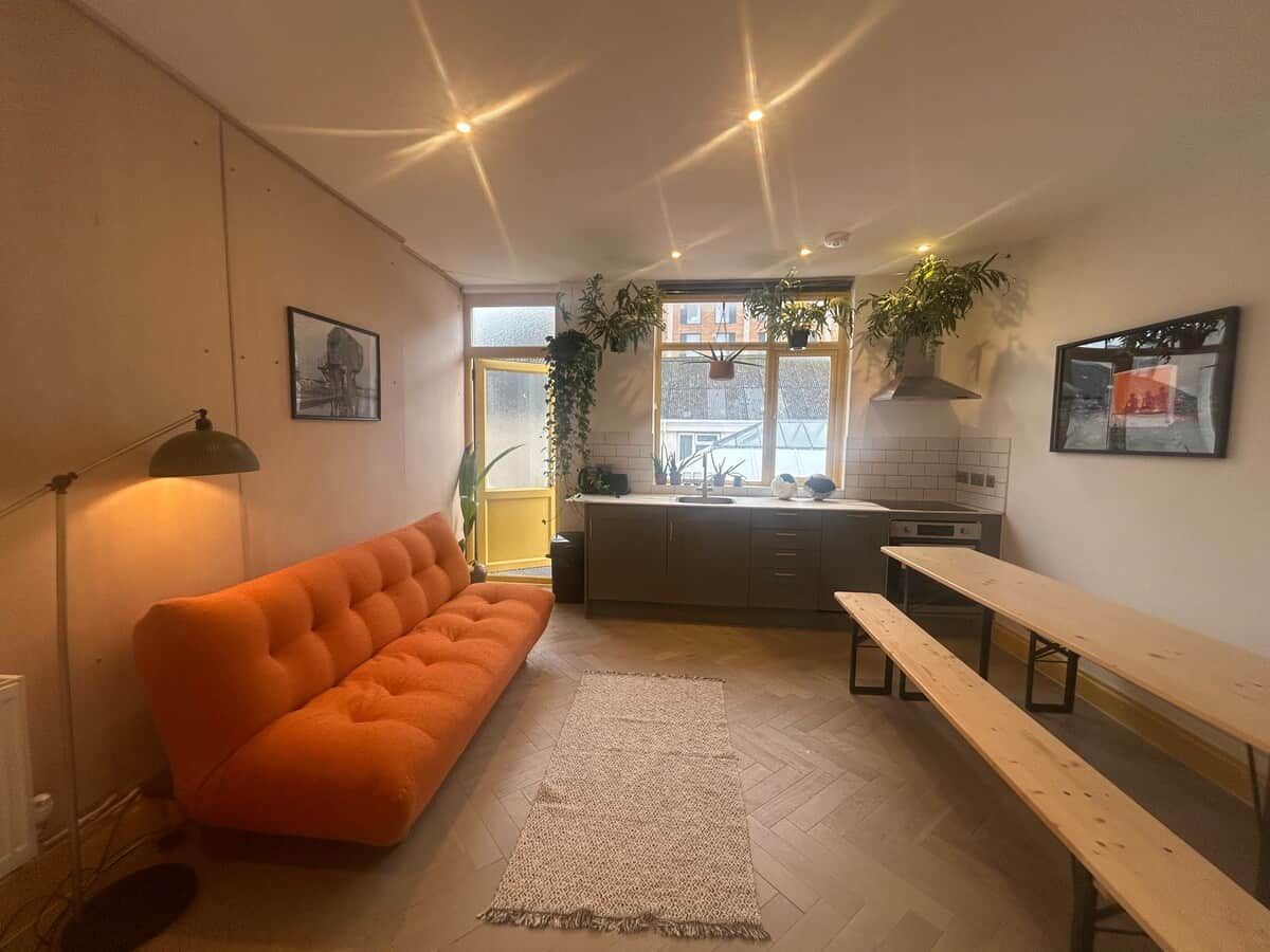 A modern kitchen with a sofa, bench, and potted plants.