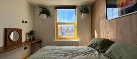 Ein Schlafzimmer mit einem Bett, einem Fenster, einer Heizung und zwei Blumentöpfen.