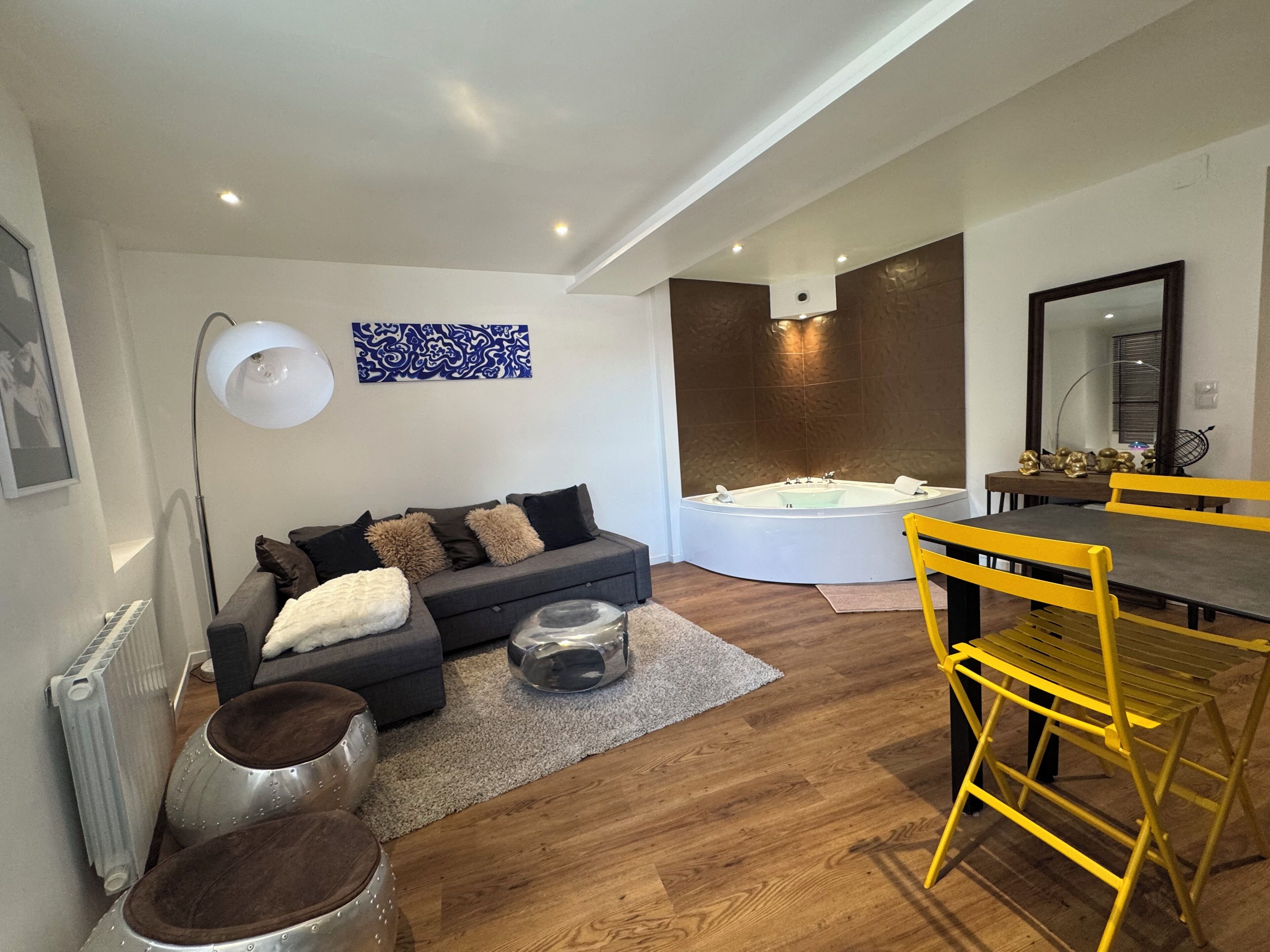 A modern living room with a sofa, a dining table with yellow chairs, a large mirror, and a bathtub.. Loft love "La Citadelle", sweet nights Bitche