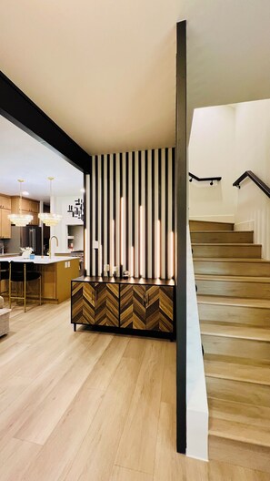 Une cuisine moderne avec des meubles en bois, un meuble dont le motif est en chevrons, et un îlot central intégré doté d’un évier.