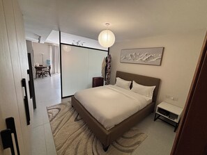 Ein modernes Hotelzimmer mit einem großen Bett, einem Nachttisch, einer Wandlampe und einem Gemälde.