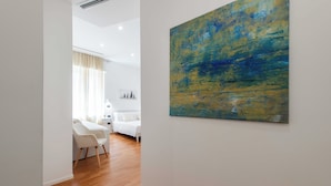 A modern room with a large abstract painting, a white sofa, and a wooden floor. - Lumen Boutique Stay (Naples)