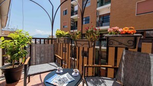 A balcony with outdoor seating, a potted plant, and a flower arrangement. - Lumen Boutique Stay (Naples)