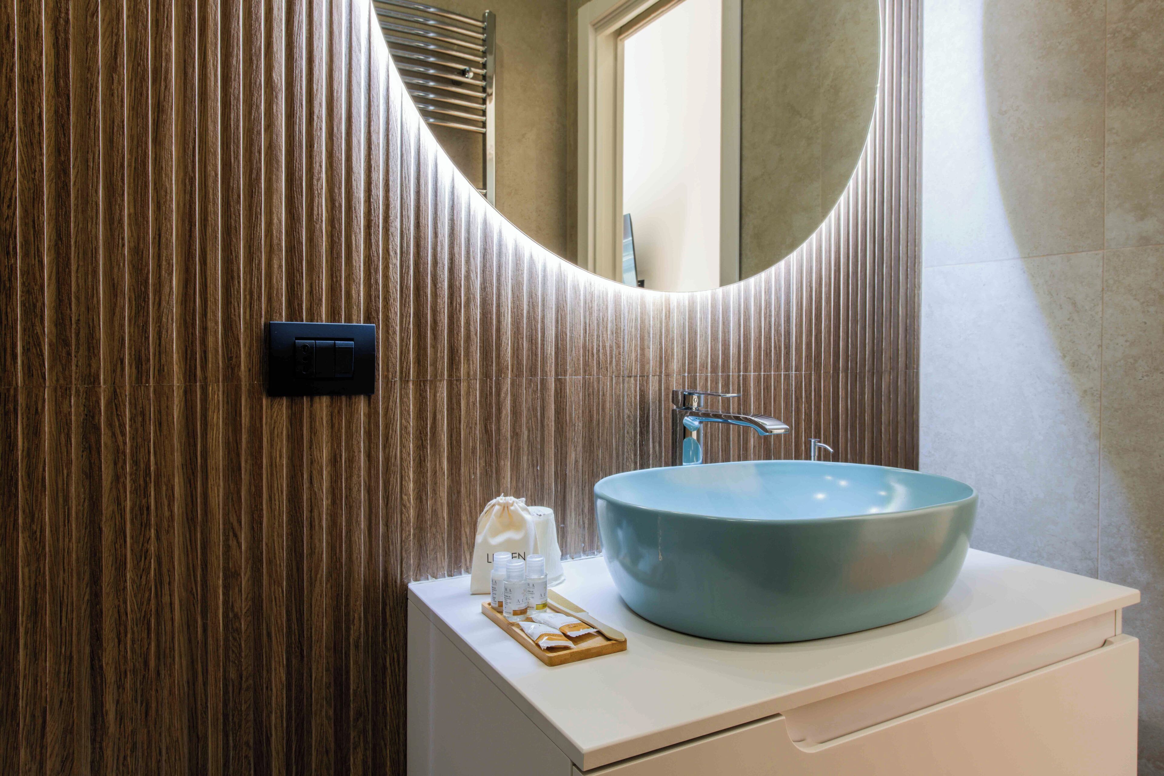 A bathroom with a wooden wall, a blue sink, a mirror, and a towel rack.