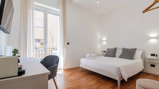 A modern bedroom with a bed, desk, chair, and a view of the outside. - Lumen Boutique Stay (Naples)