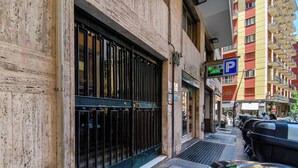 A building with a metal gate, a parking sign, and a red vehicle parked outside. - Lumen Boutique Stay (Naples)