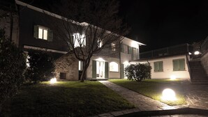A modern two-story house with a stone facade, a front entrance, and a staircase leading to an upper level. - THE HOUSE OF THE WOLF 2 | A shelter surrounded by nature (Colico)