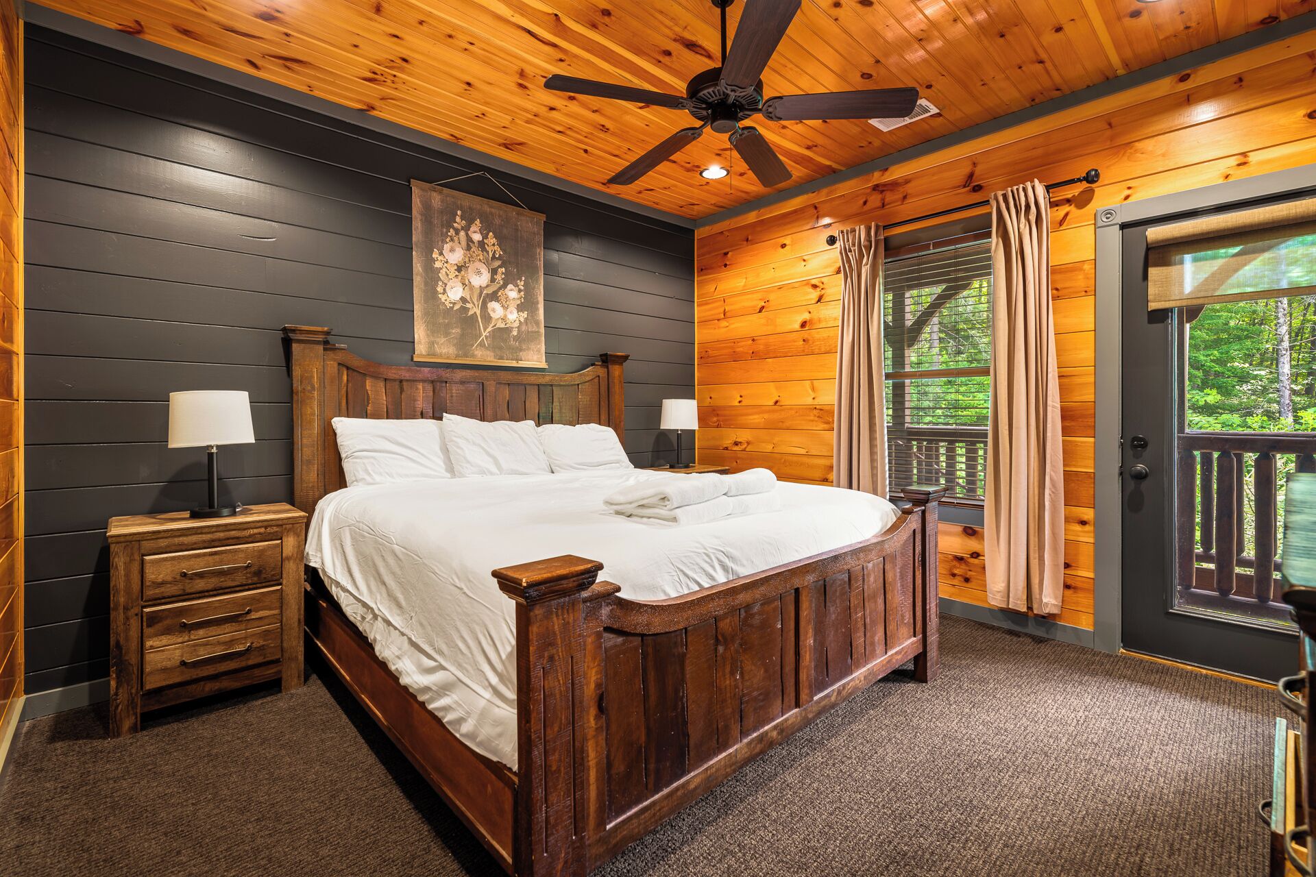 A wooden bedroom with a bed, nightstands, a ceiling fan, and a window with curtains.