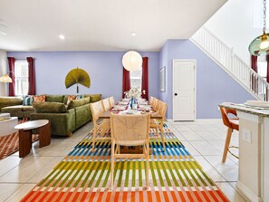 A dining area with a table set for four, surrounded by chairs, a colorful striped rug, and a fan on the wall. - Themed 6BR Cinematic Cove w Private Pool & Theater (Davenport)
