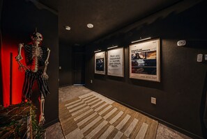 A hallway with a skeleton decoration, a poster of 'Pirate of the Caribbean: The Curse of the Black Pearl', and a quote by Carolyne Jones Breese. - Themed 6BR Cinematic Cove w Private Pool & Theater (Davenport)