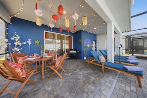 Eine Terrasse im Freien mit Esstisch, Stühlen, Liegestühlen und Lichterketten.