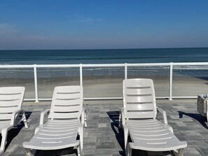 A beachside lounge area with white lounge chairs and a view of the ocean. - Cozy Quiet Beachfront Studio with Awesome Ocean View (Daytona Beach)
