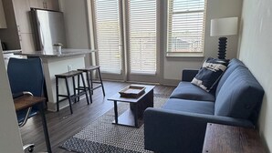 Ein modernes Wohnzimmer mit Sofa, Couchtisch und einem Essbereich mit Tisch und Stühlen.